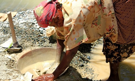 Lady washing a rock at the mining location