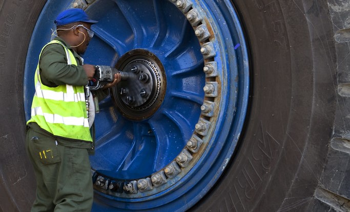 Guy fixing the the rim of a big machine tire
